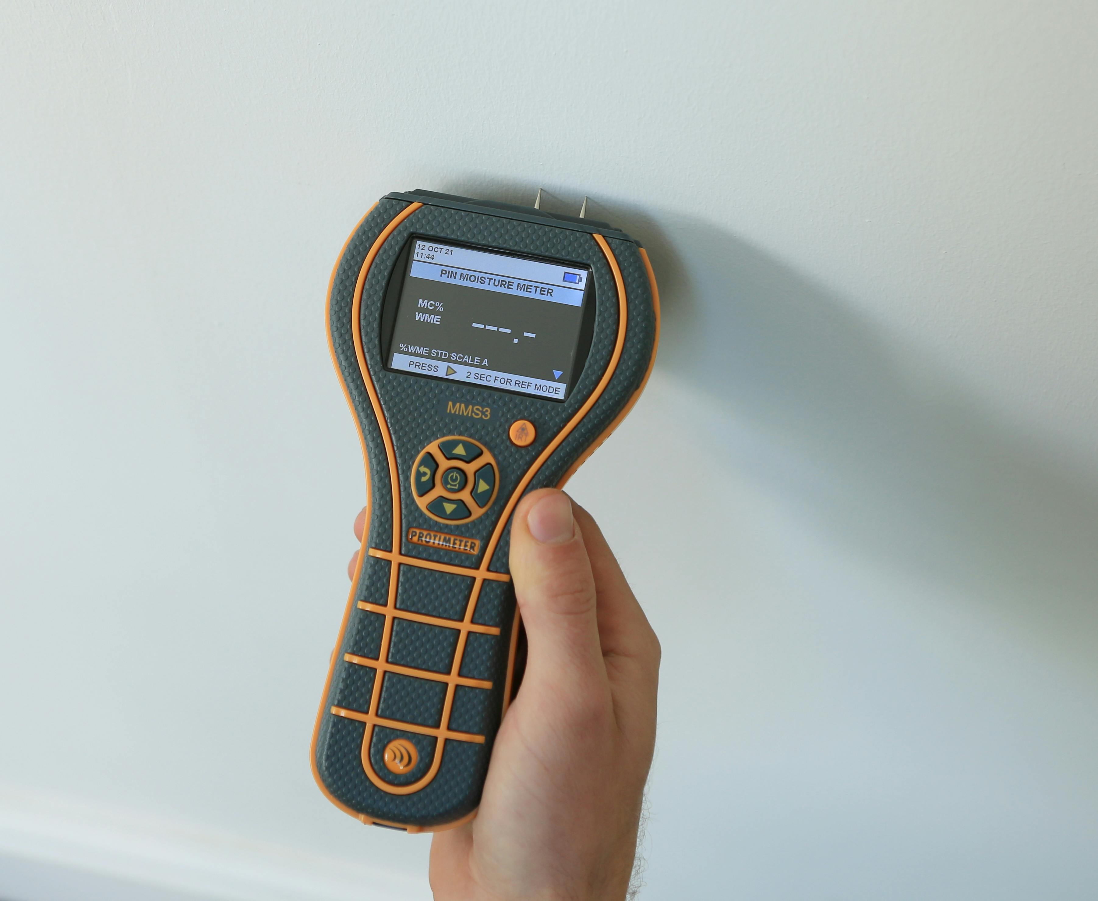 An MMS3 moisture meter checking a plaster wall